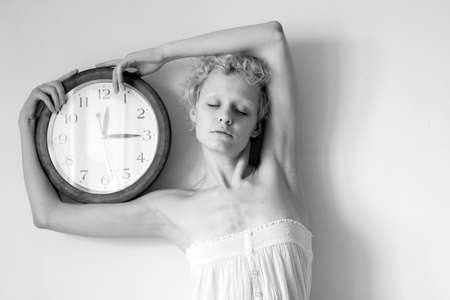 Conceptual portrait of woman with big clock (b/w photo)