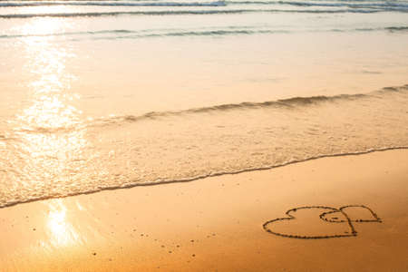Hearts drawn on the sand of a beach, soft wave of the seaの写真素材