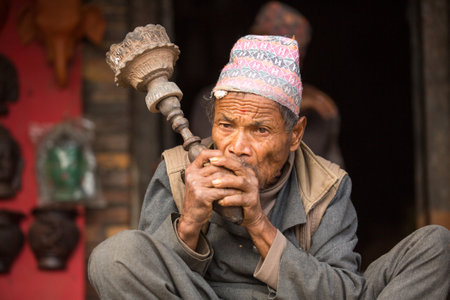 BHAKTAPUR, NEPAL - DEC 7:  Portrait of unidentified Nepalese man smokes on the street, Dec 7, 2013 in Bhaktapur, Nepal. 100 cultural groups have created an image Bhaktapur as Capital of Nepal Arts.のeditorial素材