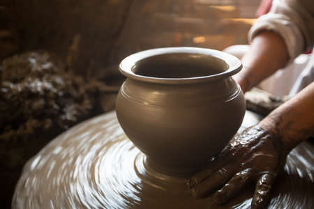 Close-up of hands working clay on potter's wheel.   