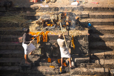 KATHMANDU, NEPAL - DEC 3: Unidentified local people during the cremation ceremony along the holy Bagmati River in Bhasmeshvar Ghat at Pashupatinath temple, Dec 3, 2013 in Kathmandu, Nepal.のeditorial素材
