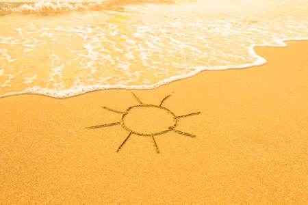 Sun drawn in the sand of a beach.の写真素材