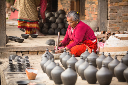 BHAKTAOUR, NEPAL - DEC 7: Unidentified Nepalese woman working in the his pottery workshop, Dec 7, 2013 in Bhaktapur, Nepal. 100 cultural groups have created an image Bhaktapur as Capital of Nepal Arts.のeditorial素材