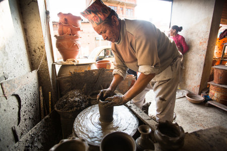 BHAKTAPUR, NEPAL - DEC 7, 2013: Unidentified Nepalese man working in the his pottery workshop. More 100 cultural groups have created an image Bhaktapur as Capital of Nepal Arts.のeditorial素材