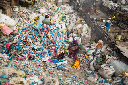 KATHMANDU, NEPAL - DEC 19, 2013: Unidentified child is sitting while her parents are working on dump. In Nepal annually die 50,000 children, in 60% of cases - malnutrition.のeditorial素材
