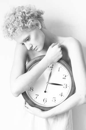 Conceptual portrait of woman in bed with big clock, b/w photo.の写真素材