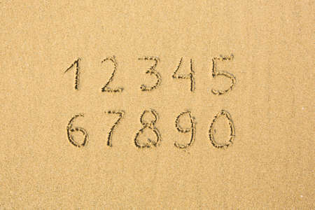 Numbers written on a sandy beach.の写真素材
