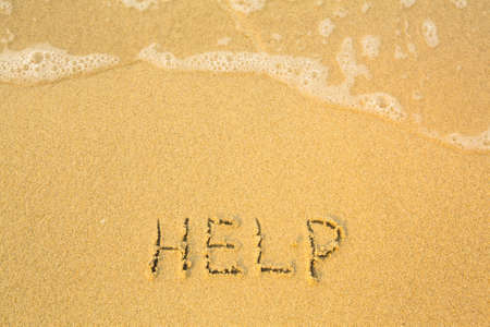 Help, written in sand on beach texture - soft wave of the sea.の写真素材