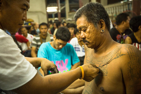 NAKHON CHAI, THAILAND - MAR 23: Unidentified monk makes traditional Yantra tattooing during Wai Kroo Master Day Ceremony in Wat Bang Pra on Mar 23, 2013 in Nakhon Chai, Thailand.のeditorial素材