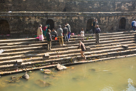 KATHMANDU, NEPAL - DEC 3: Unidentified local people during the cremation ceremony along the holy Bagmati River in Bhasmeshvar Ghat at Pashupatinath temple, Dec 3, 2013 in Kathmandu, Nepal.のeditorial素材