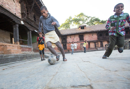 KATHMANDU, NEPAL - DEC 9, 2013: Unknown children play football after lesson at Jagadguru School. School established at 2013, to let new generation learn Sanskrit and preserve Hindu culture.のeditorial素材