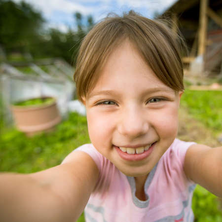 Funny little girl taking self portrait (selfie) outdoors.の写真素材