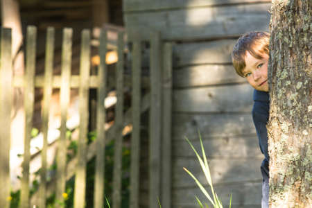 Happy child peeks from behind a tree.の写真素材