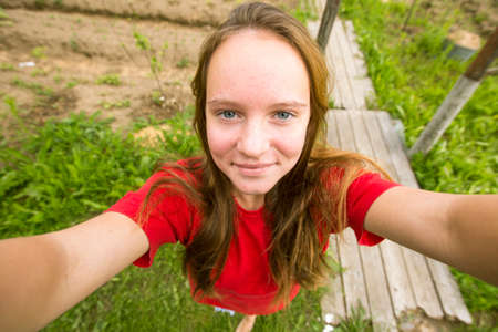 Teengirl taking a selfie (self-portrait) out in the country house.
