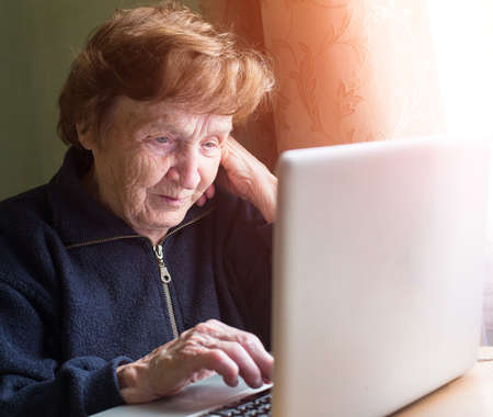 Very elderly woman sing laptop computer at home.の写真素材