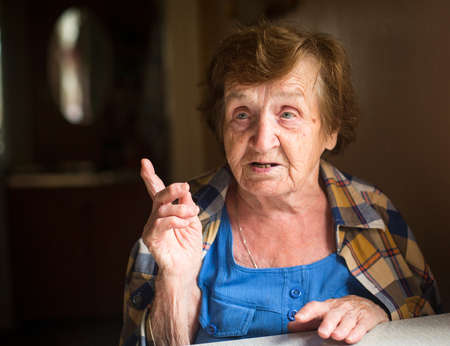 Old woman sitting at table and talk in his house.の写真素材
