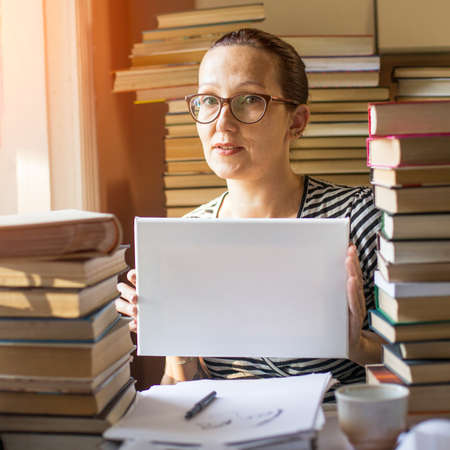 Banner for your message: Woman holding clean white sheet paper in a room with lots of books.