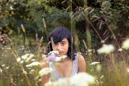 Cute young girl sitting in a meadow of flowers.