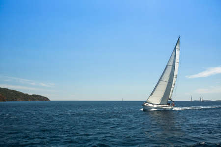 Sailing ship yachts with white sails in the open sea.