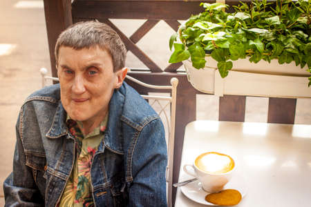 Disabled man with cerebral palsy, smiling sitting at an outdoor cafe.の写真素材