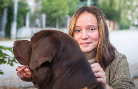 Close-up portrait of a pretty girl walking outdoors with a big dog.の写真素材