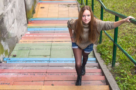 Young pretty girl on the stone steps in the city.の写真素材