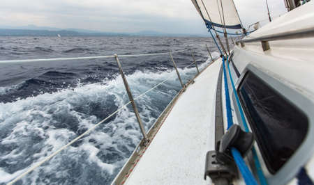 Sailing ship yachts with white sails in sea in stormy weather.の写真素材