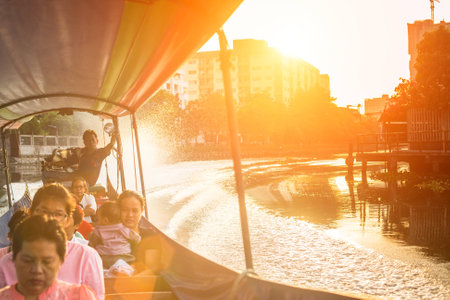 BANGKOK, THAILAND - DEC 19, 2014: A long-tail boat carrying local people passing on the Chao Praya River. Long-tail boats are a cheap (15 baht/ $0,5) form of river transport in the Thai capital.のeditorial素材
