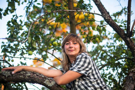 Young woman on a tree in the Apple orchard.の写真素材