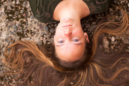 Young cute girl lying on the pavement with her long hair, top view close-up.の写真素材