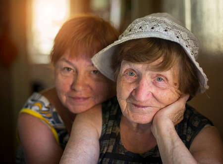 Portrait of old woman and hugging her daughter in the background, in the house.の写真素材