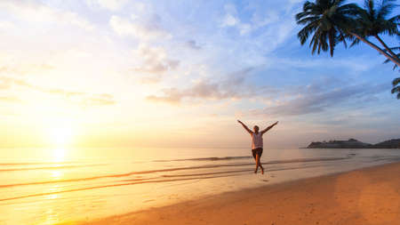 Young man happily jumping on the ocean beach. Vacation, holiday, joy.の写真素材