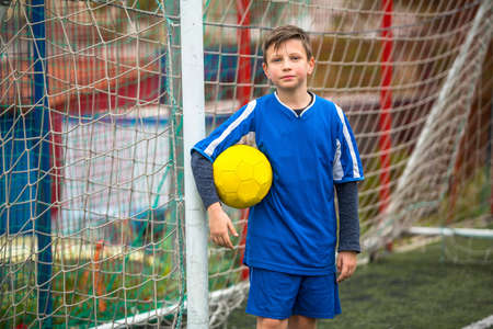 Little boy in goalkeeper uniform on football field.の写真素材