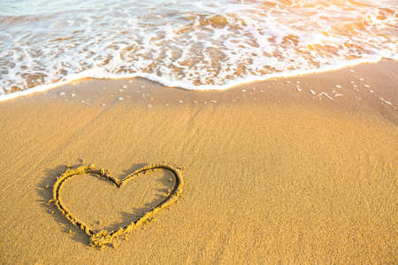 Heart drawn on the sand of a Sea beach, soft wave in a sunny day.の写真素材