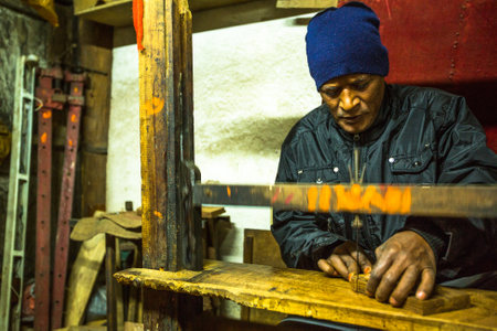 BHAKTAPUR, NEPAL - CIRCA DEC, 2013: Unidentified Nepalese man working in his wooden workshop. More 100 cultural groups have created an image of Bhaktapur as Capital of Nepal Arts.のeditorial素材