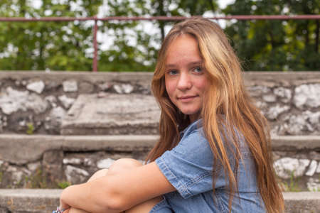 Portrait of young girl sitting on the stone steps at the old city Park.の写真素材