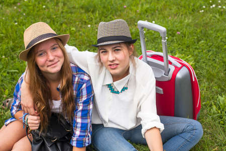 Two young girls girlfriends travellers, sitting on the grass.の写真素材