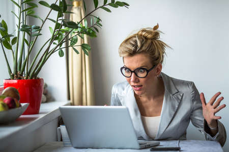 Nervous business woman screaming loudly at her laptop in office. Stress.の写真素材