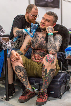 KRAKOW, POLAND - JUNE 6, 2015: People make a tattoos at the 10-th International Tattoo Convention in the Congress-EXPO Center. This year anniversary TattooFest is tattoo Studio with an area of 2000m2.のeditorial素材