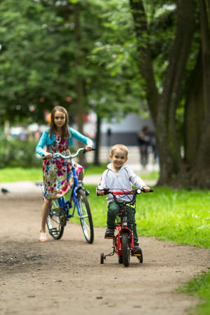 A little boy with his sister ride bikes in the Park.の写真素材