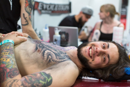 KRAKOW, POLAND - JUNE 6, 2015: People make a tattoos at the 10-th International Tattoo Convention in the Congress-EXPO Center. This year anniversary TattooFest is tattoo Studio with an area of 2000m2.のeditorial素材