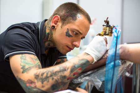 KRAKOW, POLAND - JUNE 6, 2015: People make a tattoos at the 10-th International Tattoo Convention in the Congress-EXPO Center. This year anniversary TattooFest is tattoo Studio with an area of 2000m2.のeditorial素材