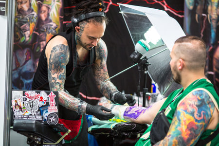 KRAKOW, POLAND - JUNE 6, 2015: People make a tattoos at the 10-th International Tattoo Convention in the Congress-EXPO Center. This year anniversary TattooFest is tattoo Studio with an area of 2000m2.のeditorial素材