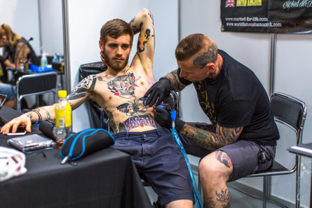 KRAKOW, POLAND - JUNE 6, 2015: People make a tattoos at the 10-th International Tattoo Convention in the Congress-EXPO Center. This year anniversary TattooFest is tattoo Studio with an area of 2000m2.のeditorial素材