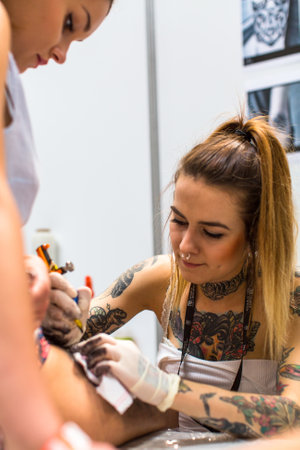 KRAKOW, POLAND - JUNE 6, 2015: People make a tattoos at the 10-th International Tattoo Convention in the Congress-EXPO Center. This year anniversary TattooFest is tattoo Studio with an area of 2000m2.のeditorial素材