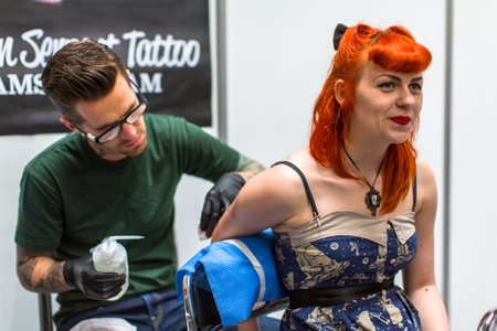 KRAKOW, POLAND - JUNE 6, 2015: People make a tattoos at the 10-th International Tattoo Convention in the Congress-EXPO Center. This year anniversary TattooFest is tattoo Studio with an area of 2000m2.のeditorial素材