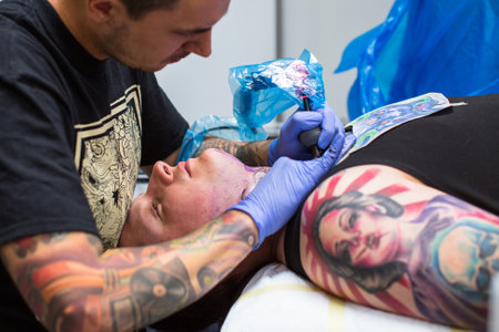 KRAKOW, POLAND - JUNE 6, 2015: People make a tattoos at the 10-th International Tattoo Convention in the Congress-EXPO Center. This year anniversary TattooFest is tattoo Studio with an area of 2000m2.のeditorial素材
