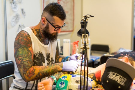 KRAKOW, POLAND - JUNE 6, 2015: People make a tattoos at the 10-th International Tattoo Convention in the Congress-EXPO Center. This year anniversary TattooFest is tattoo Studio with an area of 2000m2.のeditorial素材