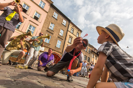 KRAKOW, POLAND - JUL 12, 2015: Participants at the annually (July 9-12) 28th International Festival of Street Theatres - Orchestre International du Vetex (Belgium/France) in the Main Square of Krakow.のeditorial素材