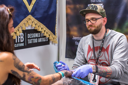 KRAKOW, POLAND - JUNE 6, 2015: People make a tattoos at the 10-th International Tattoo Convention in the Congress-EXPO Center. This year anniversary TattooFest is tattoo Studio with an area of 2000m2.のeditorial素材